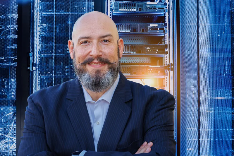 Felipe Medina stands in front of server racks with his arms crossed.