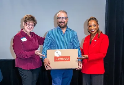 Three people pose with a Lenovo laptop box.