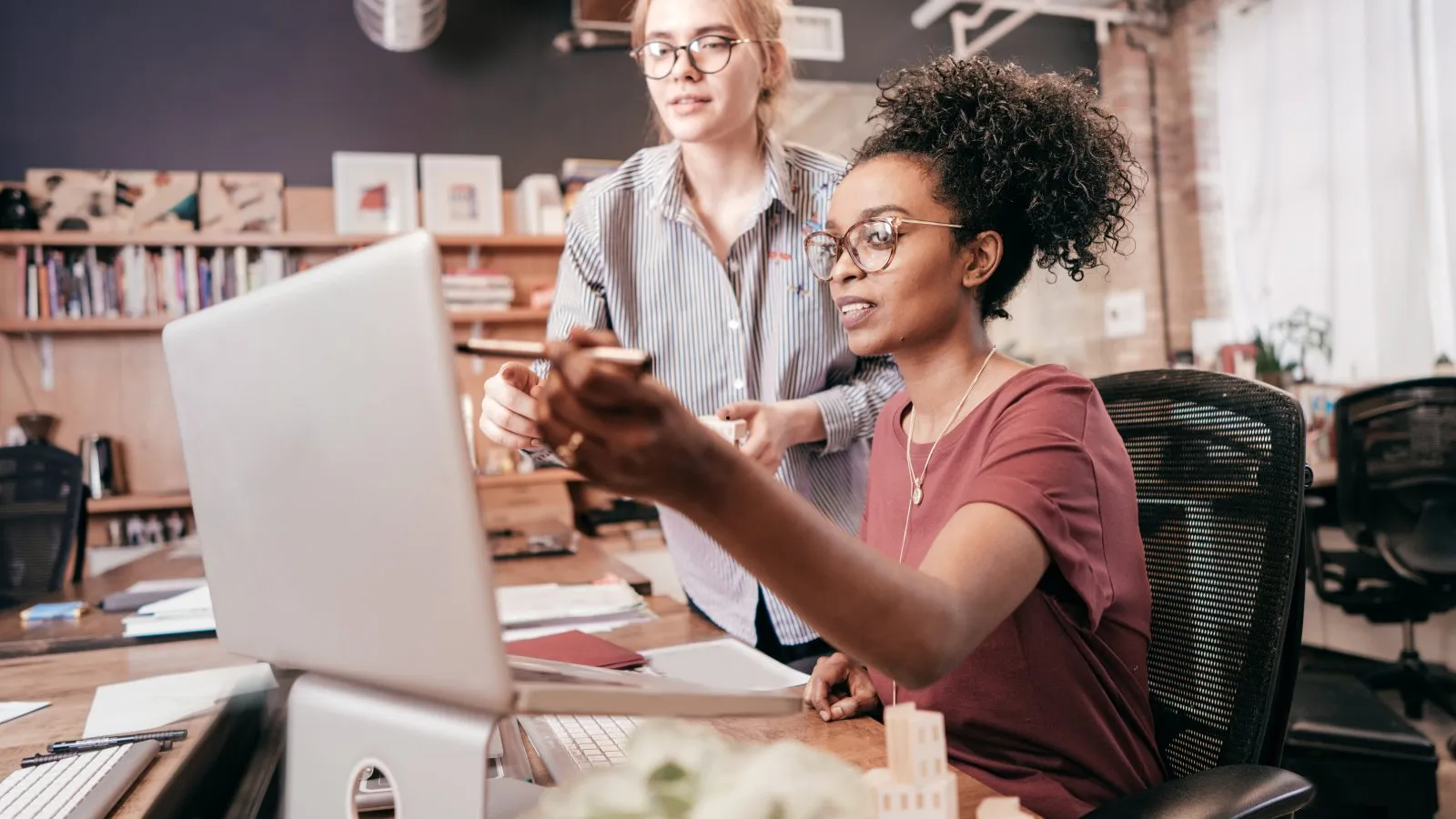 Two young women working together at a laptop in an office